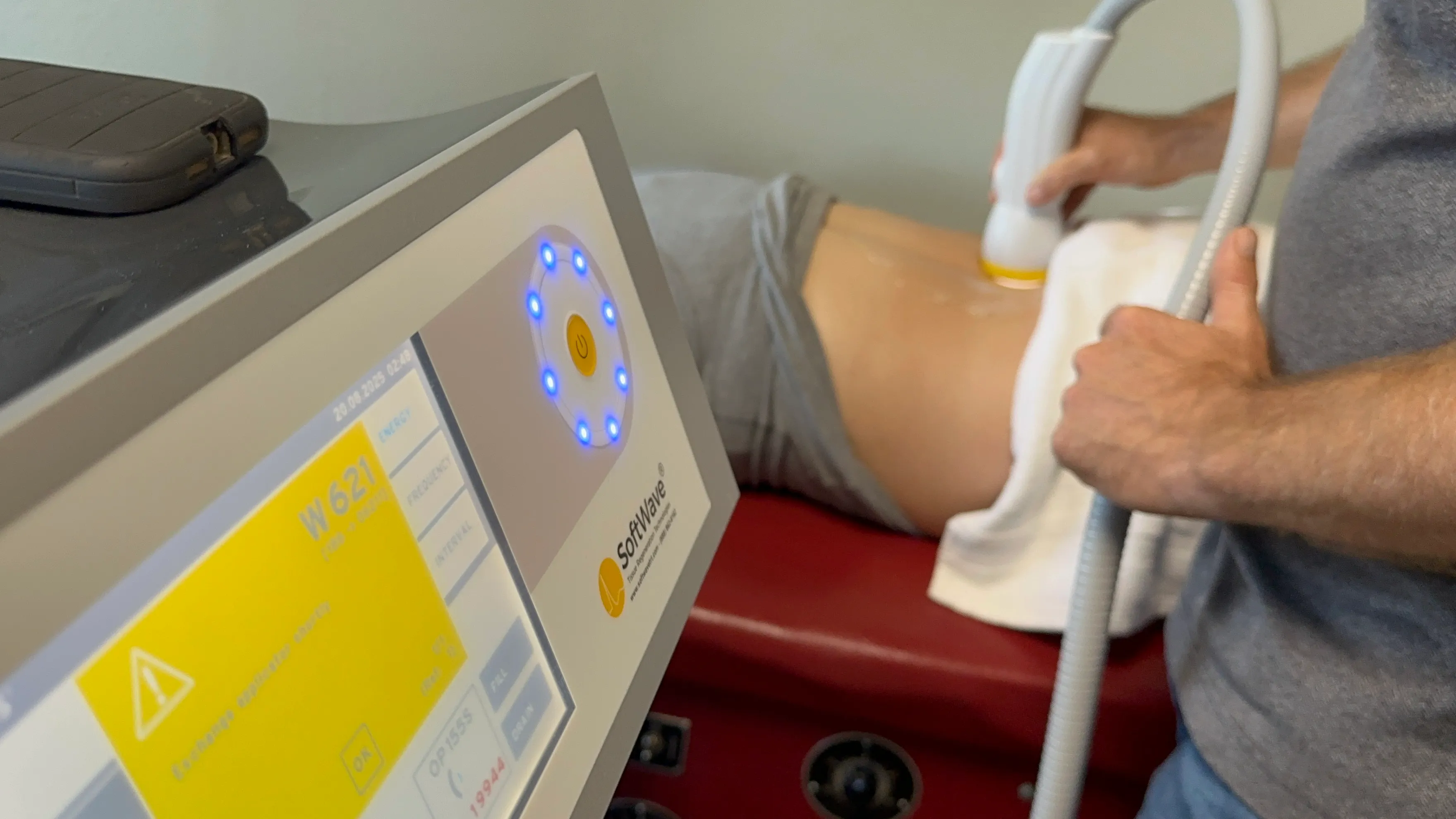 ShockWave therapy device and handheld applicator being used during an in-clinic treatment